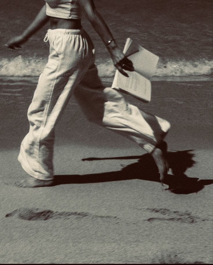 A woman walking along the shore, papers in hand